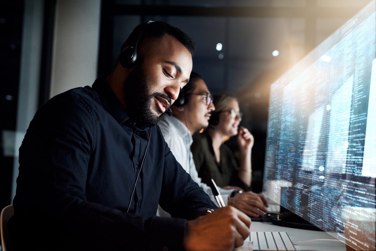 Male employee working for an IT services company using a computer to resolve issues. 