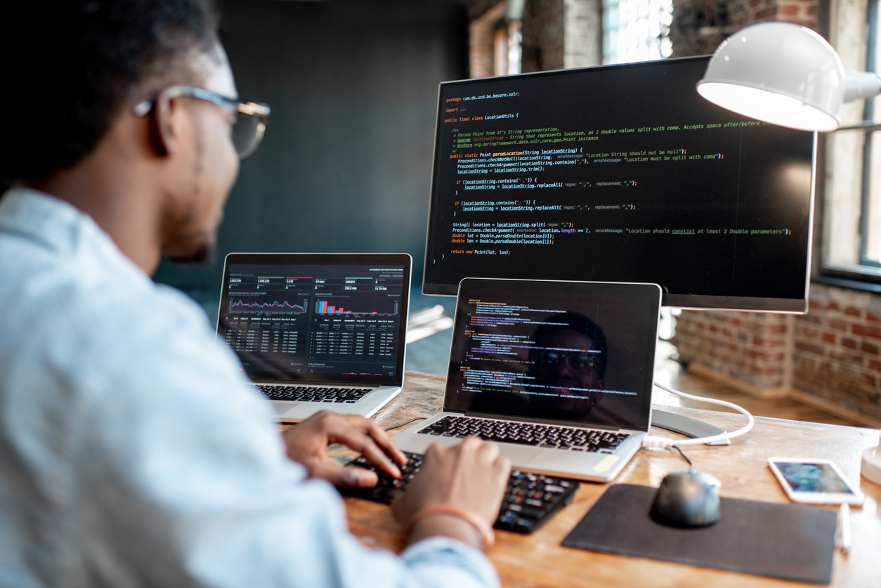 Male programmer working on network design using several computers and devices.